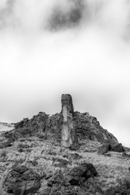 Black and white low angle of rough rocky formation in highlands under cloudy sky