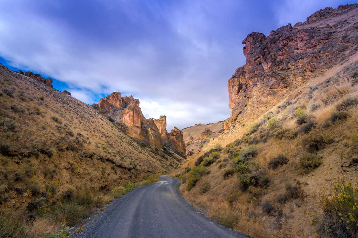 Picturesque view of curvy asphalt roadway running through hills and steep cliffs in mountainous terrain Illustrative editorial photograph.