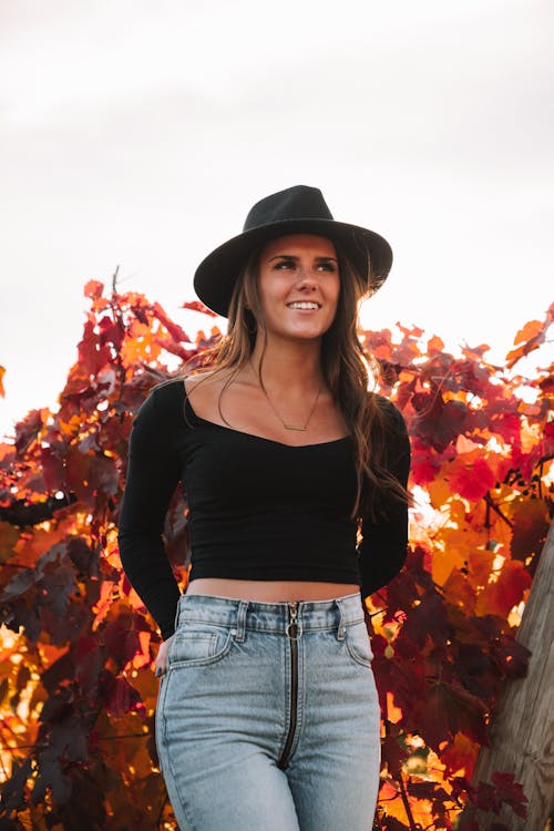 Stylish woman in hat standing in autumn park