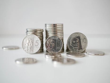 白色表面上，菲律宾比索硬币堆叠散落的特写视图