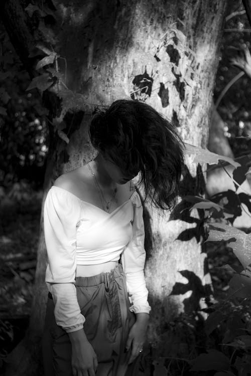 Free Anonymous upset woman covering face with hair in lush woods Stock Photo