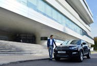 Well dressed man standing near new black car in city