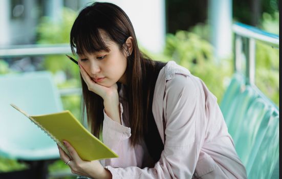 一位体贴的亚洲少女，手拿字帖和钢笔坐在街头
