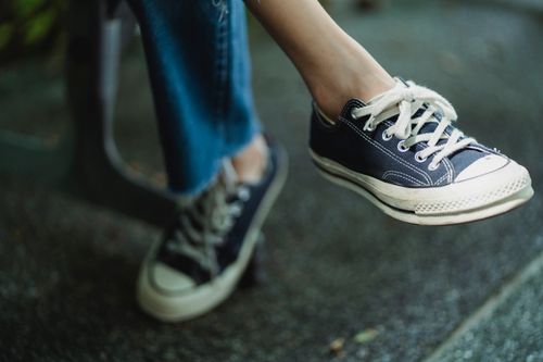 Free Crop unrecognizable person in comfortable gumshoes with white shoelaces and sole sitting in sunlight Stock Photo