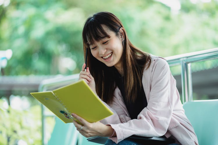 Positive Asian Student With Exercise Book Studying On Street