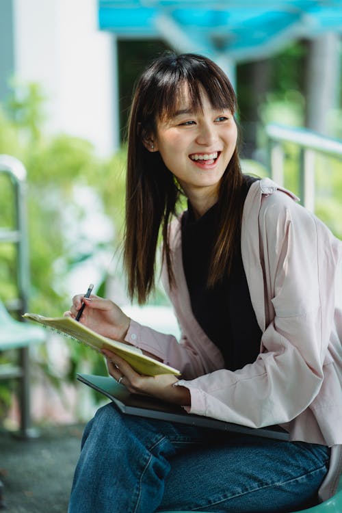 Content Asian teen with copybook on chair