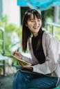 Content Asian teen with copybook on chair