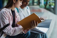 Crop diverse female students with exercise books studying on stairs