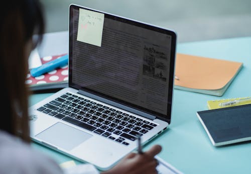 Crop multiethnic students with laptop studying at table