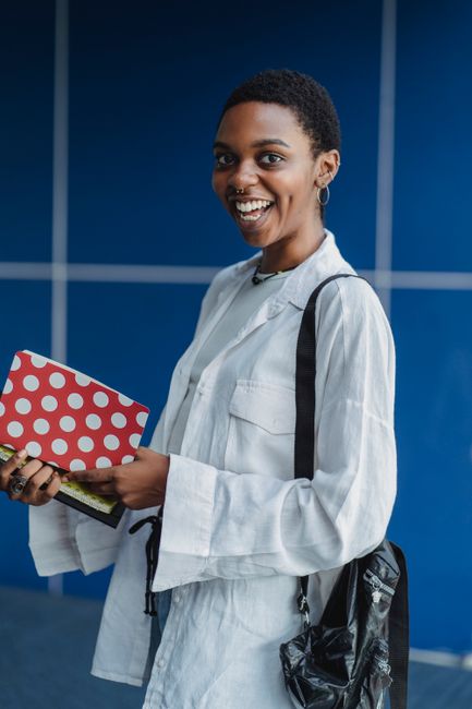 Side view of young happy African American female with exercise books and rucksack looking at camera