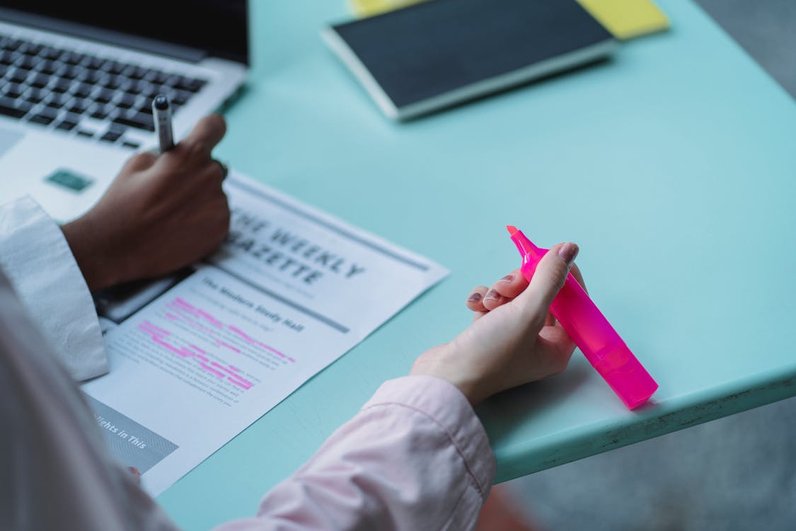 Free From above of faceless multiethnic students writing on paper sheet with text and title while studying at table Stock Photo