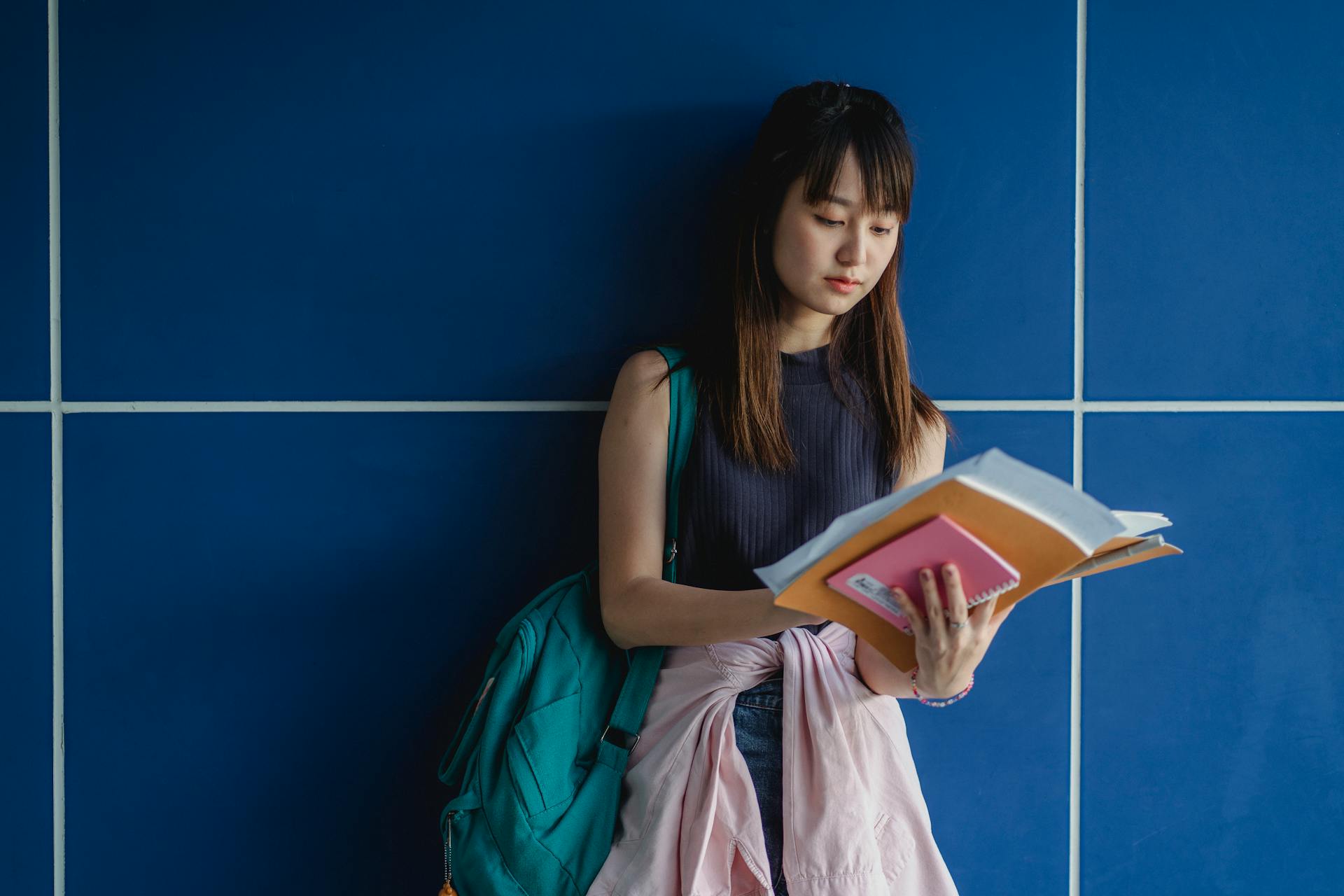 Young attentive ethnic woman in casual apparel with exercise books preparing for exams in daytime