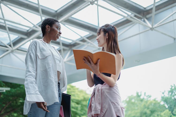 Smiling Diverse Students With Workbook Speaking Under Roof