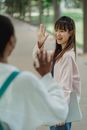 阳光明媚的公园里，两名年轻女子微笑着交换友好的问候