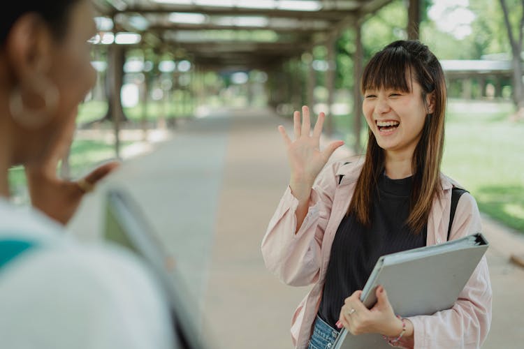 Happy Asian Woman Saying Hello To Crop Black Girlfriend