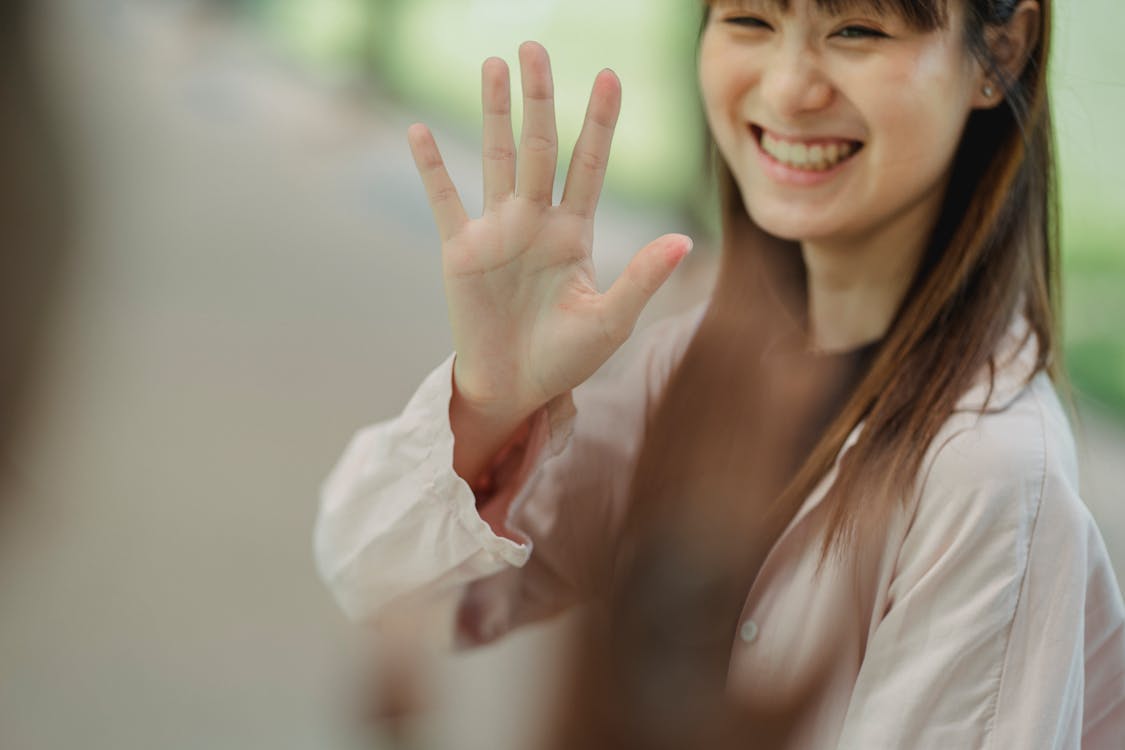 Crop smiling ethnic woman greeting unrecognizable black friend on street