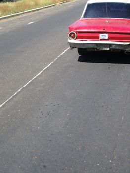 A classic red car parked on an empty road in Venezuela, showcasing vintage car design.