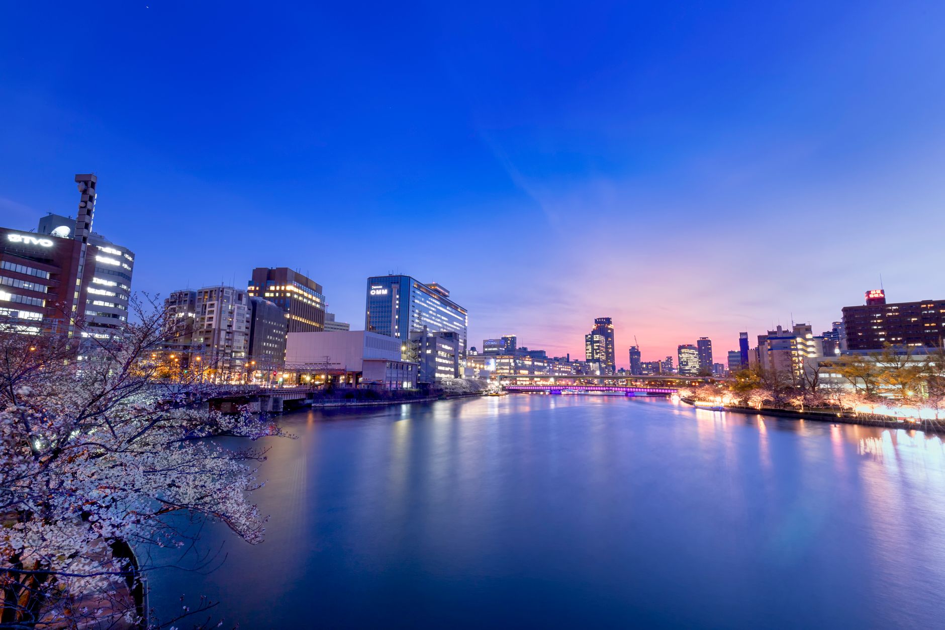 Illuminated buildings reflected on a river at dusk