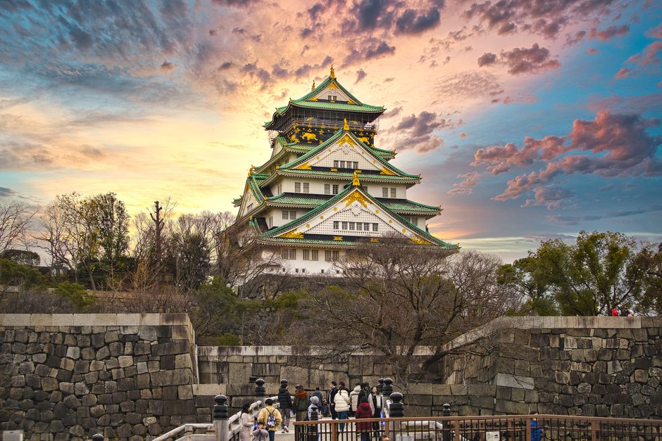 観光客を惹きつける、鮮やかな夕日と共に映し出された大阪城。象徴的な日本の建築。