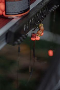 Detailed shot of fishing hooks with colorful baits hanging on a rack, highlighting fishing gear essentials.