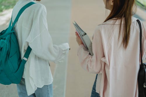 Crop unrecognizable female students strolling on walkway