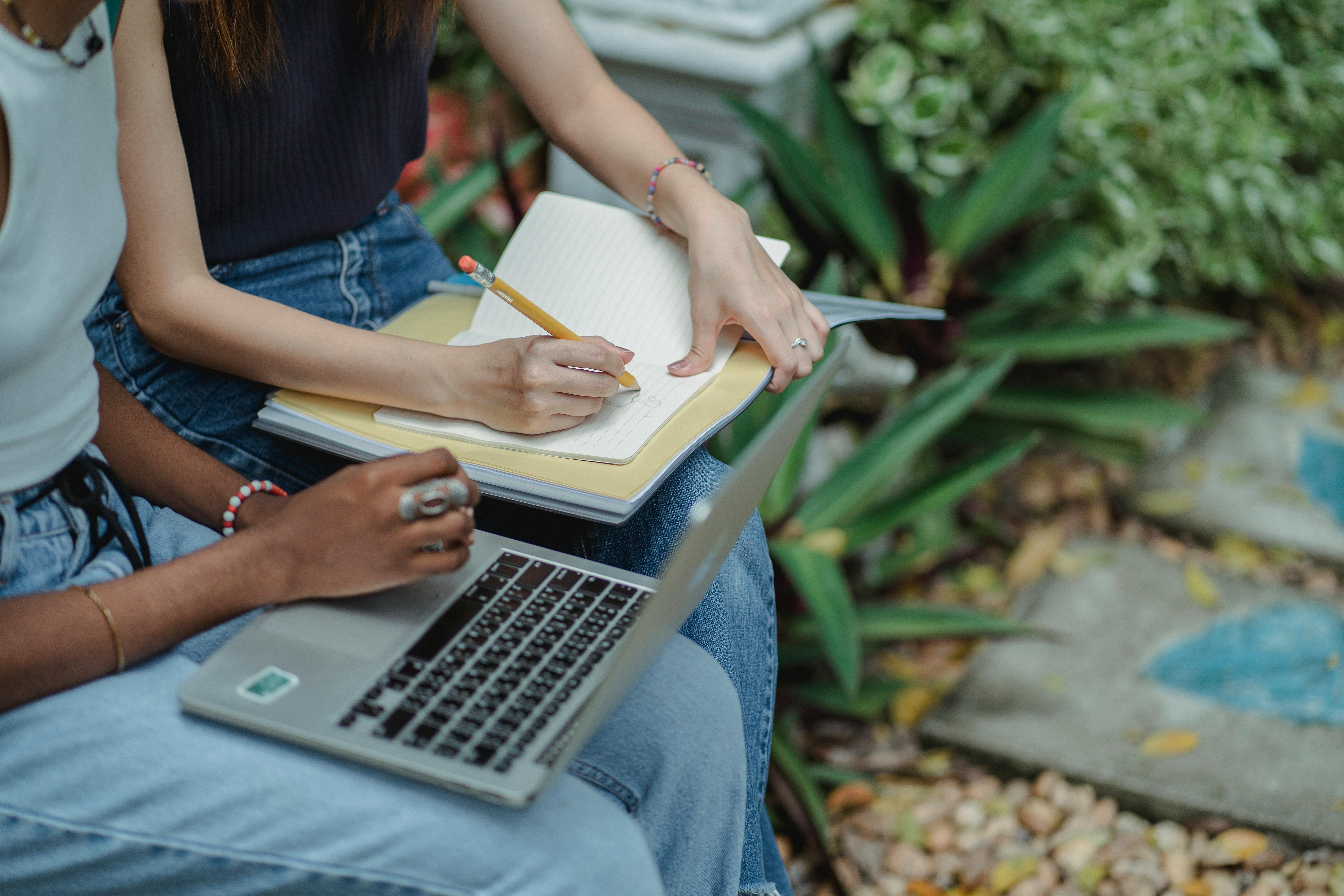 crop unrecognizable diverse female students working on project in park