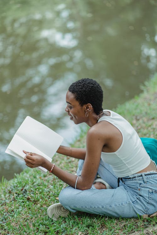 African American woman sitting on grass with sketchbook