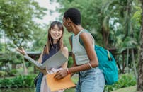 Multiracial women walking on street with folder and sketchpad