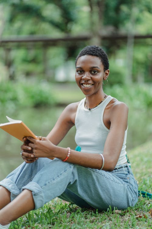 Black woman sitting on grass with notepad in hands