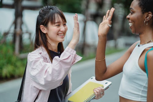 Multiethnic girlfriends standing on street and giving high five