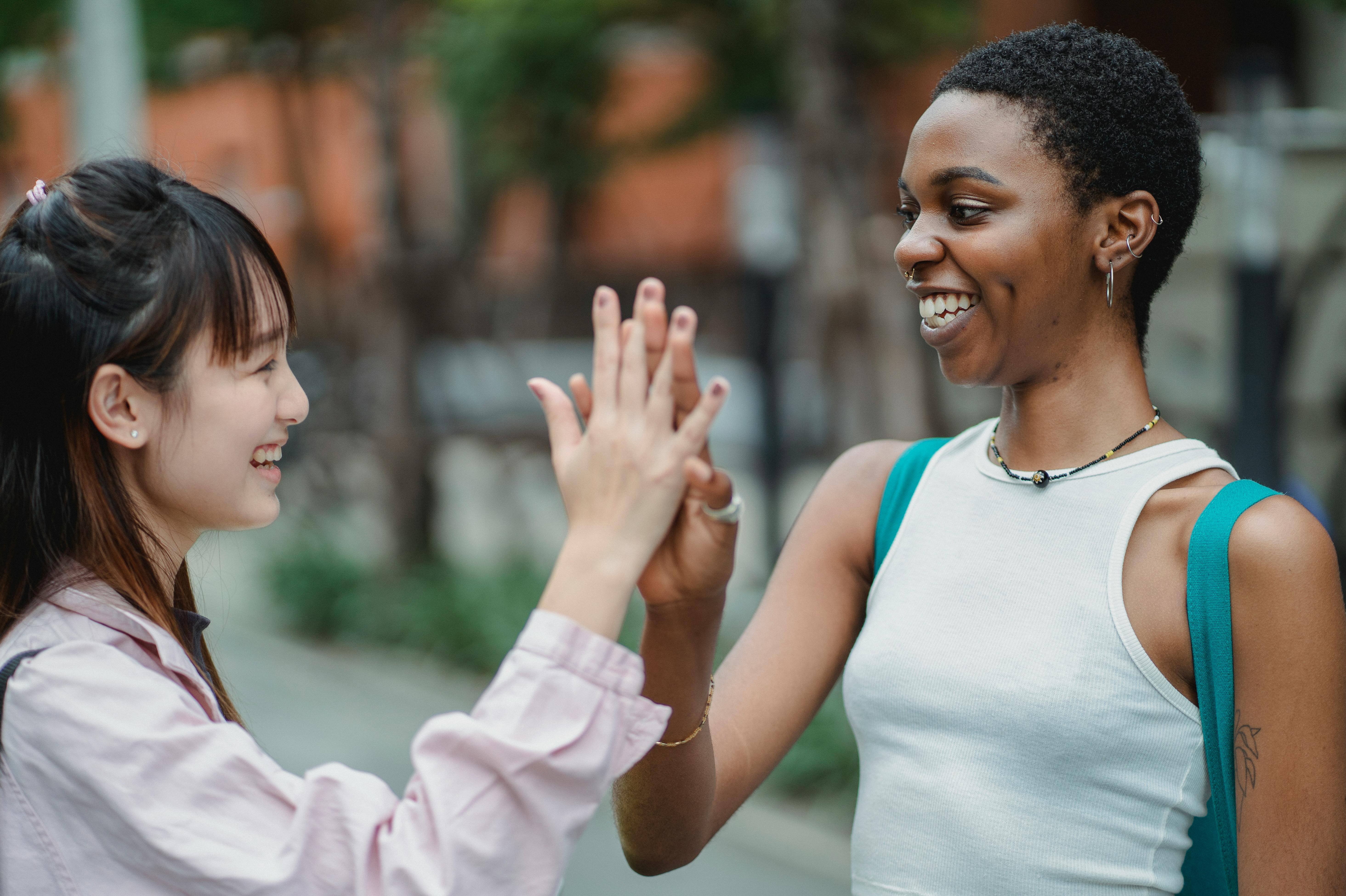 multiracial women giving high five on street