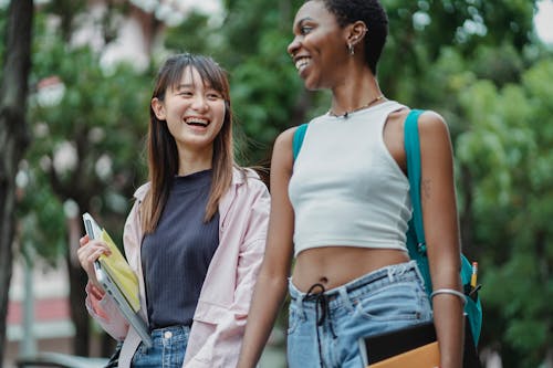 Free Joyful multiethnic students chatting happily and walking in park Stock Photo