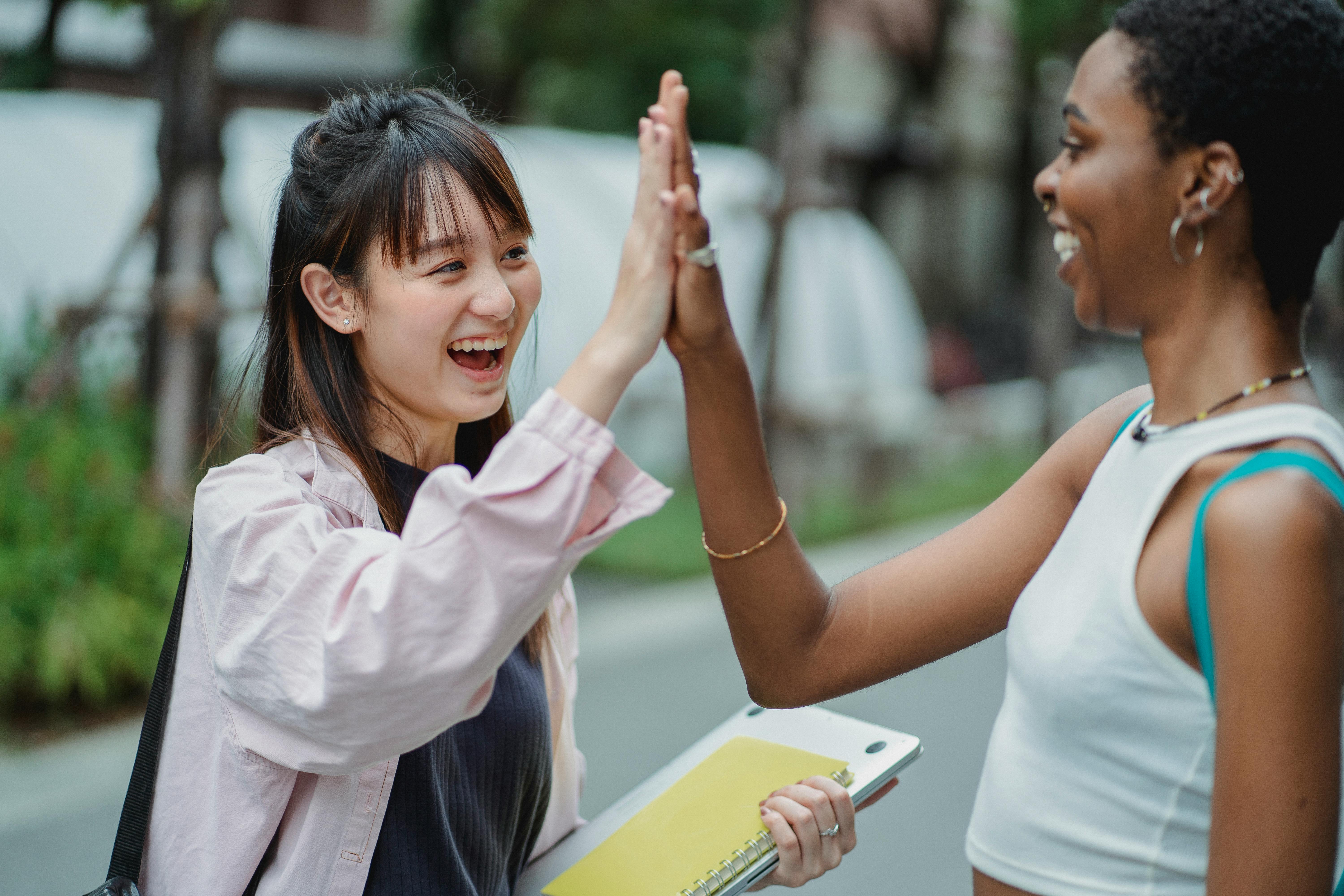 joyful diverse students giving high five in park
