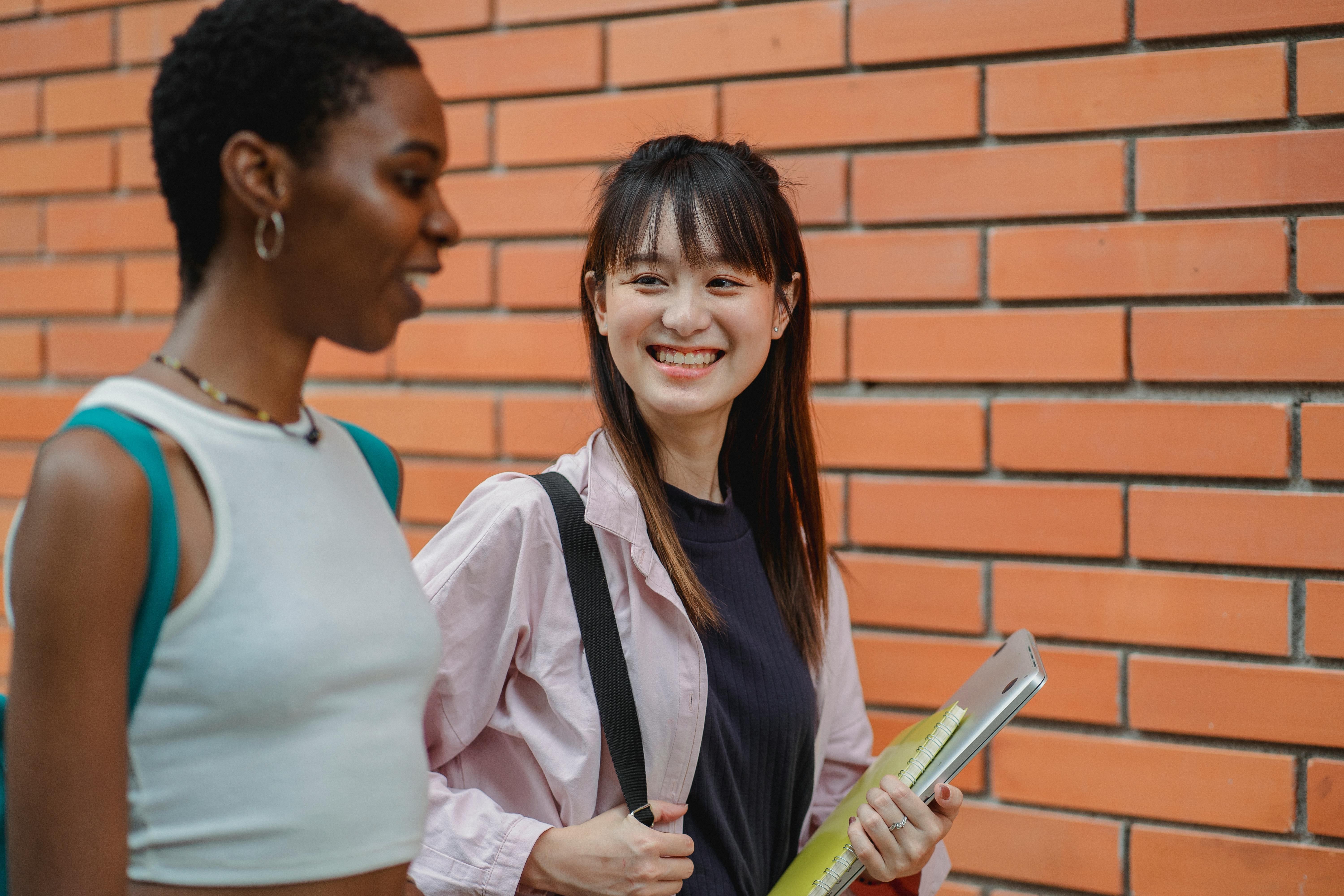 happy multiethnic students chatting and outside brick building