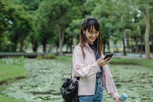 Positive ethnic woman with smartphone and earphones