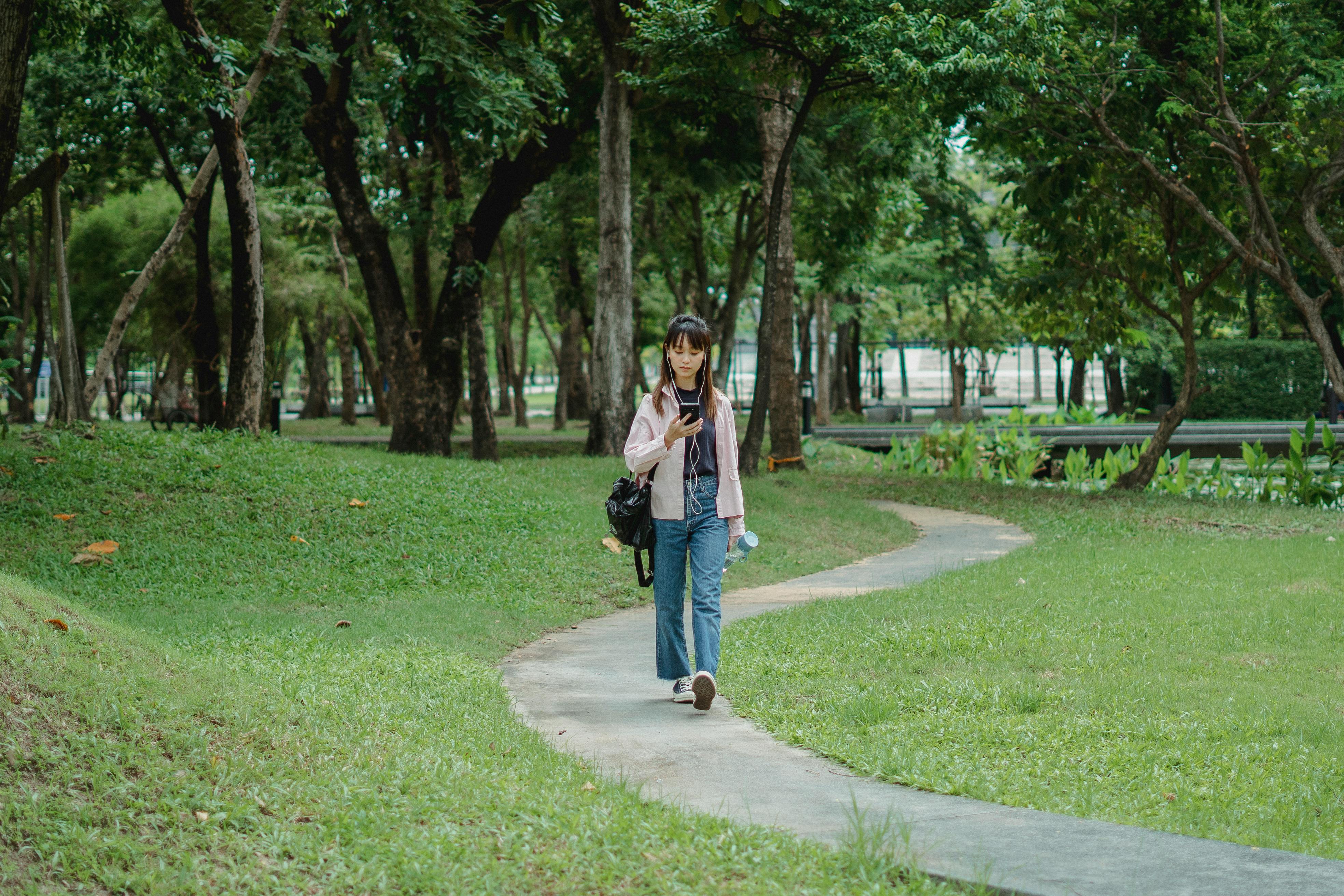 concentrated woman text messaging while strolling in park