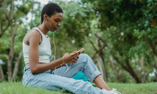 Mulher Negra Focada Com Smartphone No Gramado