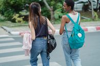 几位年轻女性朋友穿着休闲装、背着背包，一边说笑一边过马路