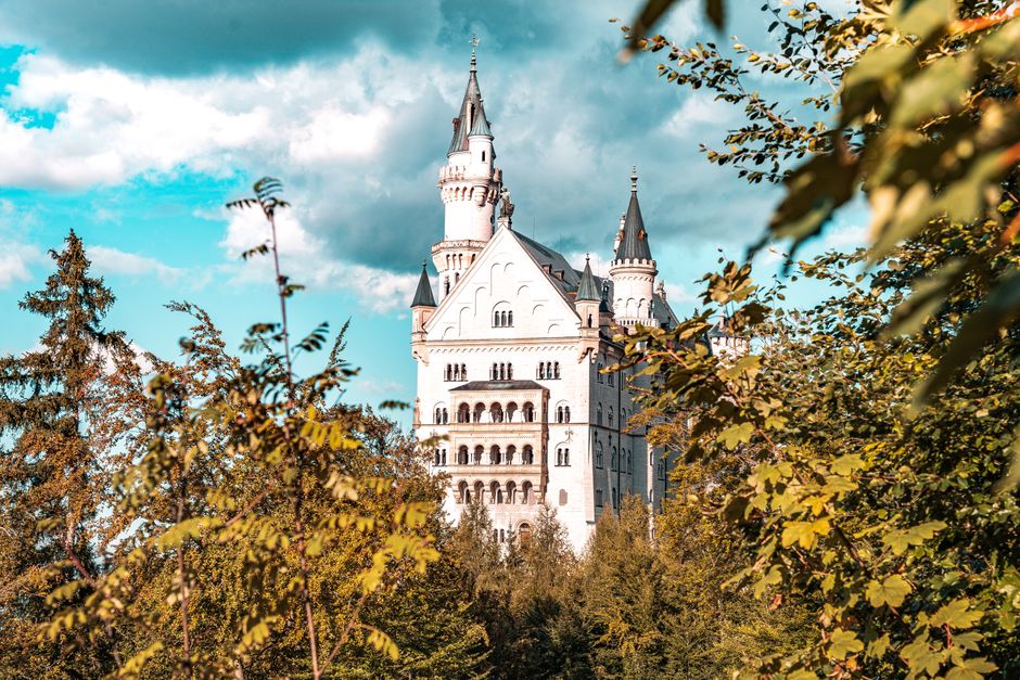 A stunning view of Neuschwanstein Castle amidst vibrant trees, under a clear blue sky.