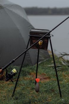 Fishing gear setup with rod and reel by a lake, ready for a peaceful fishing day.