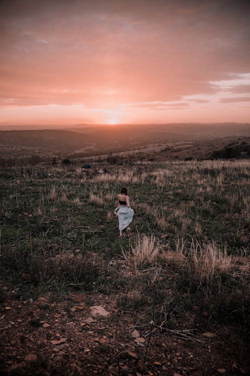 A Woman Walking on the Grass Field