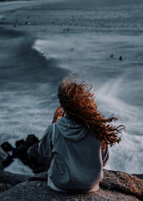 Woman sitting on rocks gazing at the Cape Town ocean, embracing nature.