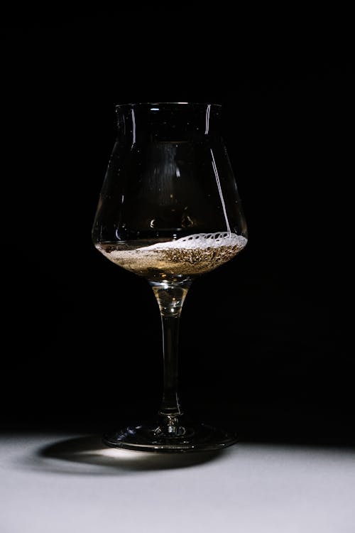 A Clear Wine Glass With Brown Liquid Inside