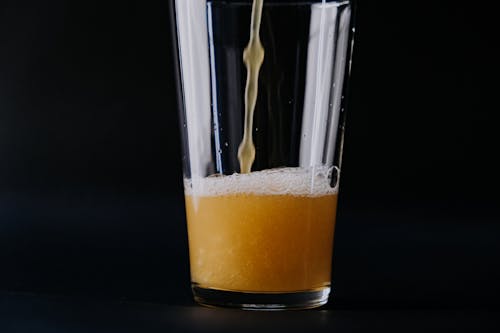 Clear Drinking Glass With Yellow Liquid and White Bubbles