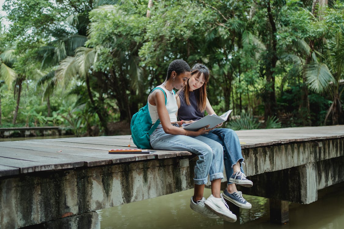 Multiethnic friends reading copybook with interest