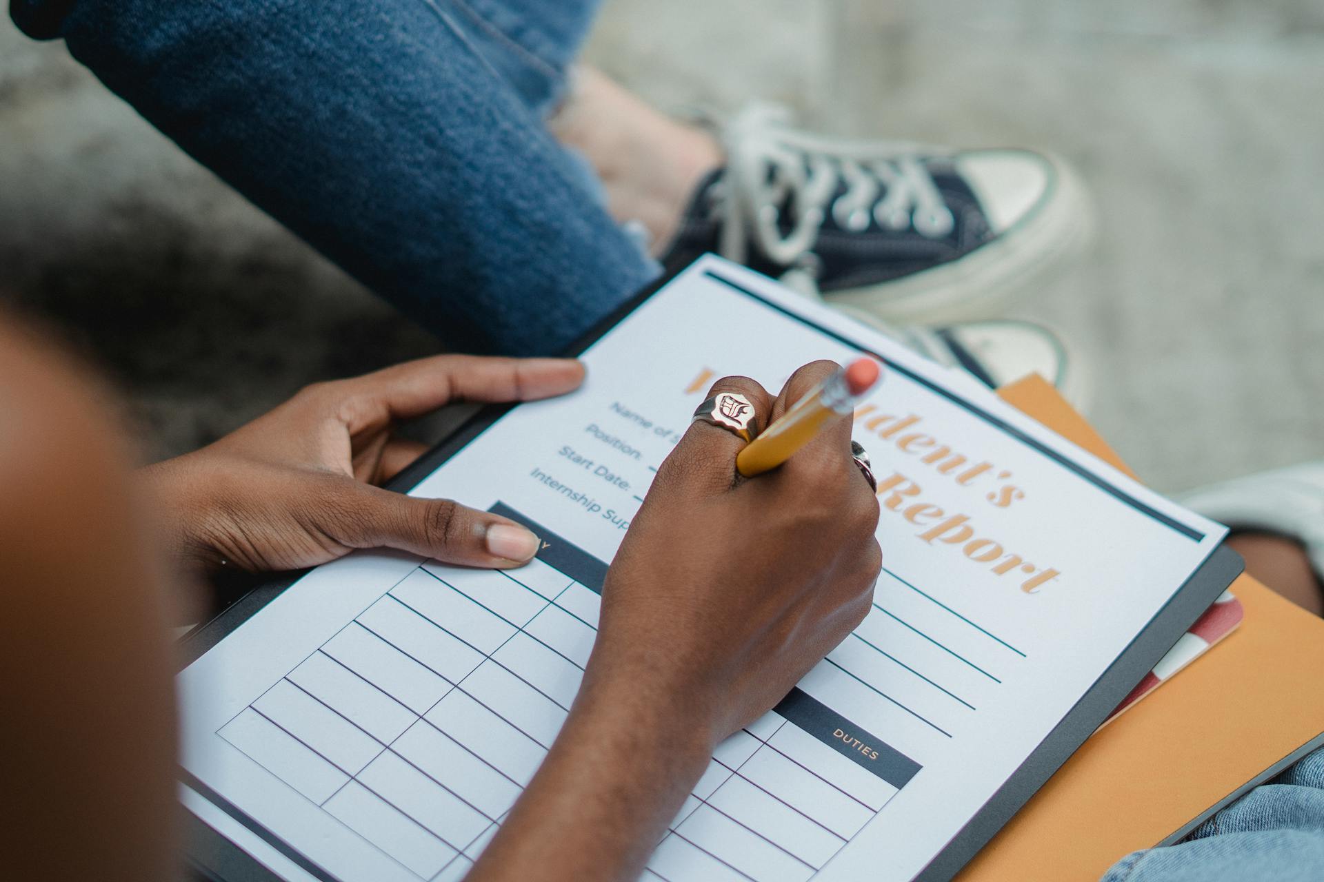 A student diligently writes on a report form outdoors while focusing on the task.