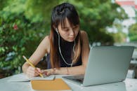 Focused woman with laptop and notebook