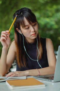 一位富有洞察力的年轻女子带着笔记本电脑和耳机在户外学习