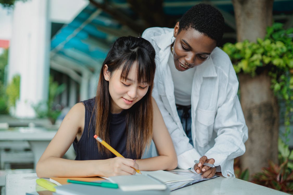 Multiethnic girlfriends preparing for exam outdoors