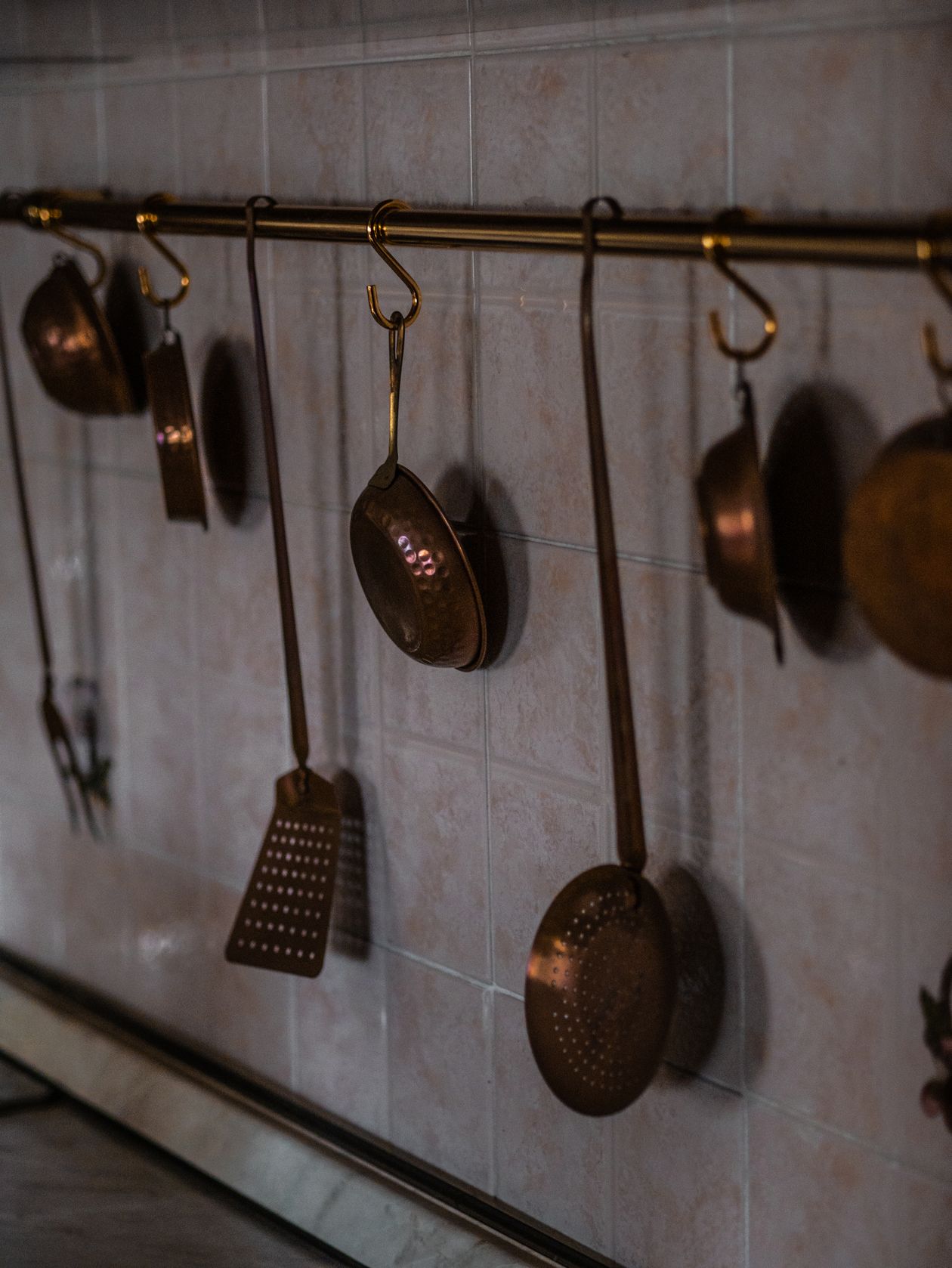 Copper kitchen utensils hanging on a rail